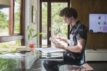 Молодой человек с цифровым планшетом работает в домашнем офисе — стоковое фото
