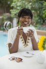 Портрет щаслива молода жінка п'є каву біля басейну — стокове фото
