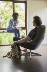 Casal jovem com cão falando e usando tablet digital no escritório em casa — Fotografia de Stock