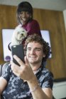 Joyeux jeune couple avec chien vidéo bavardage avec téléphone intelligent — Photo de stock