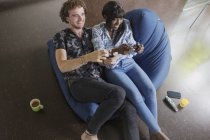Feliz joven pareja jugando videojuego en la silla beanbag - foto de stock