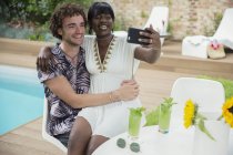 Счастливая молодая пара делает селфи с камерой телефона у бассейна — стоковое фото
