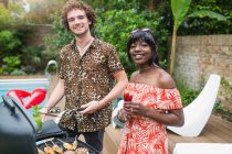 Portrait happy young couple barbecuing at poolside — Stock Photo