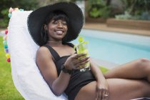 Retrato hermosa joven mujer relajante con cóctel en la piscina - foto de stock