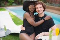 Retrato feliz joven pareja multiétnica relajarse en la piscina - foto de stock
