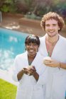 Portrait happy young couple in bathrobes drinking from coconuts — Stock Photo