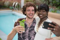 Joyeux jeune couple prenant selfie avec téléphone caméra au bord de la piscine — Photo de stock