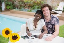 Portrait happy young multiethnic couple at poolside — Stock Photo