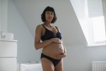 Красива вагітна жінка в бюстгальтері і трусиках тримає живіт — стокове фото