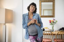 Портрет, улыбающийся беременной женщине в столовой — стоковое фото