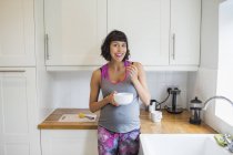 Portrait happy pregnant woman eating in kitchen — Stock Photo