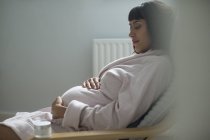 Ніжна вагітна жінка в халаті тримає живіт — стокове фото
