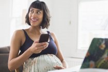 Счастливая беременная женщина с помощью смартфона — стоковое фото