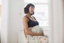 Thoughtful pregnant woman holding stomach — Stock Photo