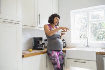 Donna incinta che mangia in cucina — Foto stock