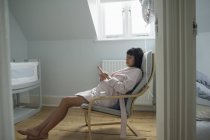 Heitere Schwangere im Bademantel entspannt im Kinderzimmer — Stockfoto