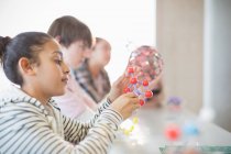 Menina curiosa examinando modelo de molécula em sala de aula — Fotografia de Stock