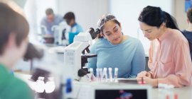 Insegnante femminile e studentessa che conduce esperimenti scientifici al microscopio in laboratorio — Foto stock