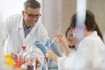 Male science teacher and students conducting scientific experiment in laboratory classroom — Stock Photo