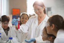 Smiling female chemistry teacher and students conducting scientific experiment in laboratory classroom — Stock Photo