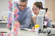 Male teacher helping girl student at microscope in laboratory classroom — Stock Photo