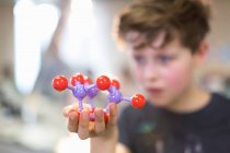 Boy student holding and examining molecular structure — Stock Photo