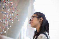 Pensif, fille curieuse étudiant examinant la structure moléculaire — Photo de stock