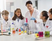 Female teacher and students conducting scientific experiment in laboratory classroom — Stock Photo