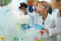 Удивленные, любопытные студенты, наблюдающие за химической реакцией, проводящие научные эксперименты в лабораторном классе — стоковое фото