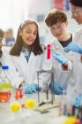 Estudantes curiosos conduzindo experimentos científicos, observando líquido em frasco para injetáveis em sala de aula de laboratório — Fotografia de Stock