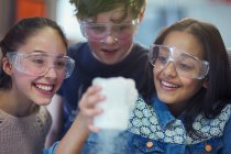 Любопытные, улыбающиеся студенты, наблюдающие за химической реакцией, проводящие научные эксперименты в лабораторных классах — стоковое фото
