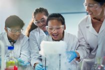 Étudiants curieux et souriants regardant la réaction chimique, menant des expériences scientifiques en classe de laboratoire — Photo de stock