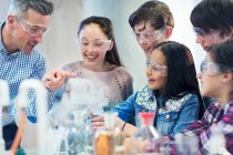 Учитель и ученики мужского пола наблюдают за химической реакцией, проводят научные эксперименты в лабораторном классе — стоковое фото