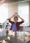 Retrato brincalhão menina estudante segurando estrutura molecular na cabeça ao microscópio em sala de aula de laboratório — Fotografia de Stock