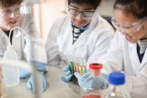 Students examining liquids in test tube rack, conducting scientific experiment in laboratory classroom — Stock Photo