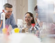 Male science teacher and students laughing, conducting scientific experiment in laboratory classroom — Stock Photo