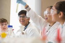 Estudantes examinando líquido em tubo de ensaio, realizando experiência científica em sala de aula de laboratório — Fotografia de Stock