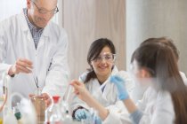 Insegnante maschio e studenti che conducono esperimenti scientifici in classe di laboratorio — Foto stock