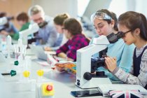 Estudiantes usando microscopio, llevando a cabo experimentos científicos en el aula de laboratorio - foto de stock