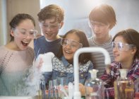 Étudiants surpris conduisant une expérience scientifique, regardant la réaction chimique en laboratoire en classe — Photo de stock