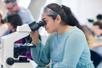 Estudiante usando microscopio, llevando a cabo experimentos científicos en el aula de laboratorio - foto de stock
