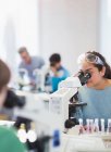 Студентка с помощью микроскопа проводит научный эксперимент в лабораторном классе — стоковое фото