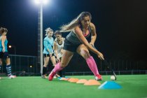 Focused young female field hockey players practicing sports drill on field — Stock Photo