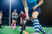 Young female field hockey players practicing sports drill on field — Stock Photo