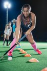 Focused young female field hockey player practicing sports drill on field — Stock Photo