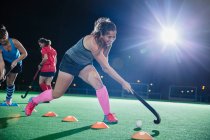 Визначений молода жінка на полі хокеїстка, що практикує спортивне тренування на полі вночі — стокове фото