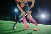 Young female field hockey players practicing sports drill on field at night — Stock Photo