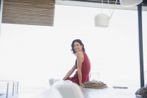 Ritratto sorridente, fiduciosa donna bruna in abito rosso seduta a tavola — Foto stock