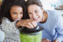 Mother and daughter making healthy green smoothie in blender — Stock Photo