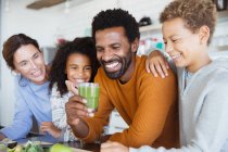 Famiglia multietnica che beve sano frullato verde in cucina — Foto stock